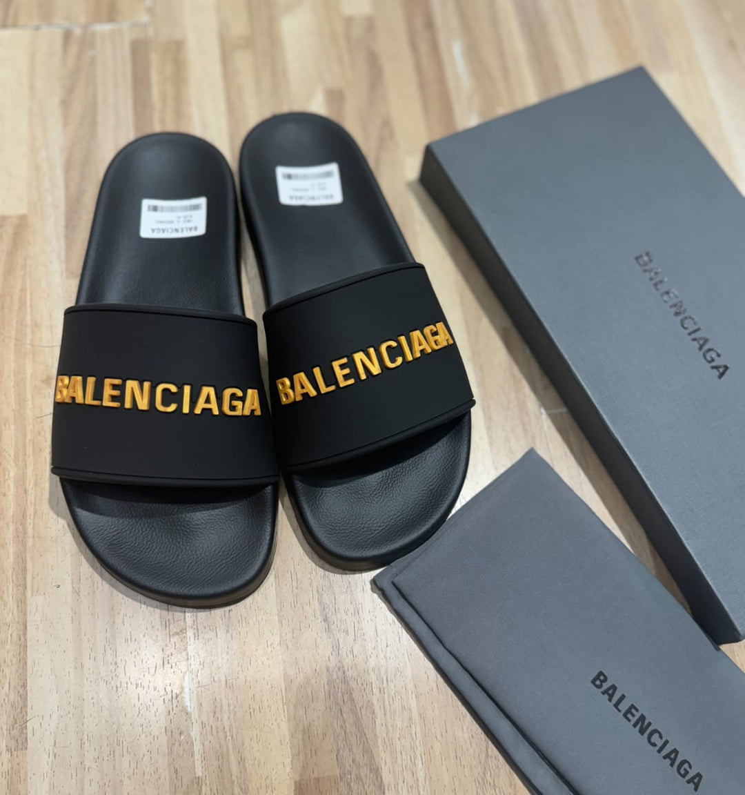 Flat slides in black rubber embossed with the Balenciga logo in gold - uaessss